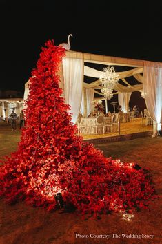 a very tall red tree with some lights on it's sides and a chandelier hanging from the ceiling