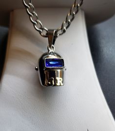 a silver necklace with a blue glass in the center on a white cloth covered surface