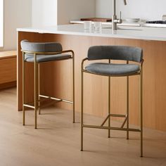 two bar stools sitting next to each other in front of a kitchen counter top