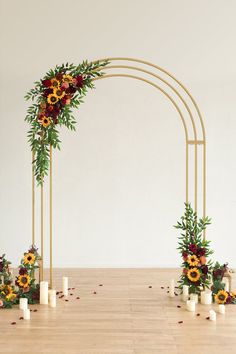 an arch decorated with sunflowers and greenery for a wedding or ceremony in front of a white wall