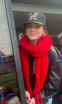 a woman wearing a red scarf and hat in the stands at a football game with other people