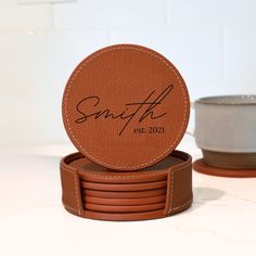 a stack of brown coasters sitting on top of a table next to a cup