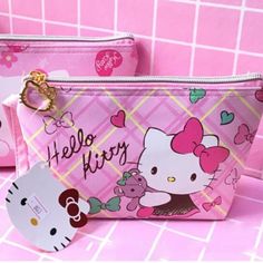 two hello kitty purses are sitting on a pink surface with hearts and bows around them