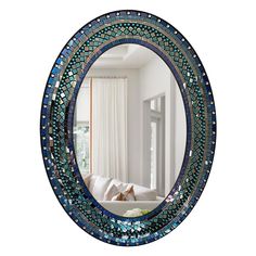 a round mirror with blue and green mosaic tiles on the frame in front of a window