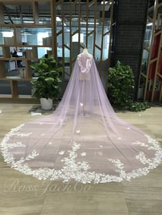 a wedding veil with white flowers on the bottom is displayed in front of a window