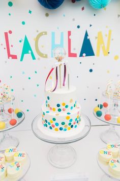 a birthday cake sitting on top of a table next to confetti and balloons