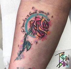 a colorful rose with an arrow and some words on the side of her arm that says, love is found within