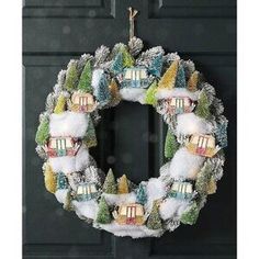 a wreath hanging on the front door of a house decorated with snow and christmas decorations