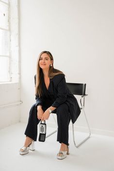 a woman sitting in a chair holding a cell phone