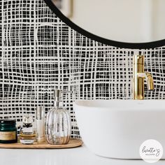 a white sink sitting next to a mirror on top of a bathroom counter under a black and white checkered wall