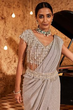 Indulge in glamour with this silver drape sari in lycra, adorned with intricate embroidery. The half-on-side tassels add a playful touch to the ensemble. The outfit is both padded and secured with a hook-eye closure, ensuring a comfortable fit. Complete the look with the embellished belt, adding a chic and stylish accent to this stunning outfit. Drape Sari, Silver Saree, Pearl Embroidery, Embellished Belt, Drape Saree, Indian Wedding Wear, Tailored Design, Stunning Outfits, Indian Design