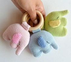 three knitted toys are being held by a person's hand on a white surface