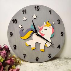 a clock with a unicorn on the face and stars around its neck, sitting next to flowers