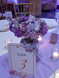 the table is set with purple flowers and candles for an elegant wedding or special event