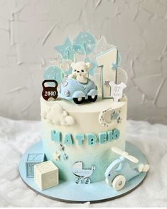 a blue and white cake with a baby's first birthday decoration on the top