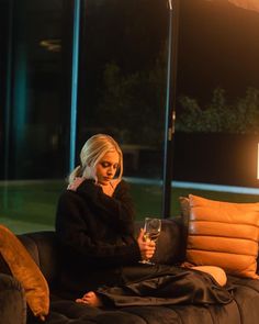 a woman sitting on a couch holding a glass of wine