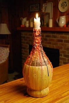 a small vase with a lit candle in it sitting on a wooden table next to a fireplace