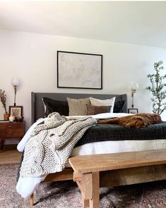 a dog laying on top of a bed next to a wooden table and dressers