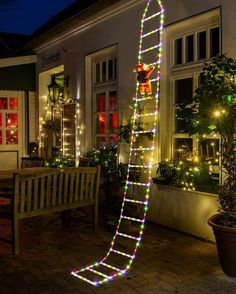 a ladder decorated with christmas lights in front of a house