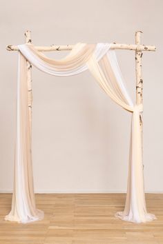 a white and pink wedding arch with sheer drapes