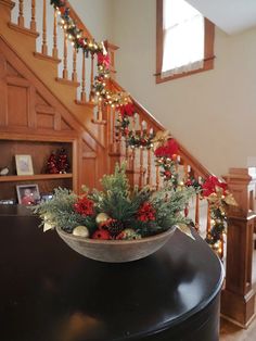 a christmas arrangement in a bowl on top of a piano