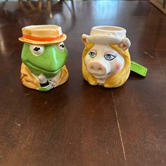 two ceramic figurines sitting on top of a wooden table