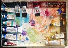 an artist's palette with paint and watercolors on it