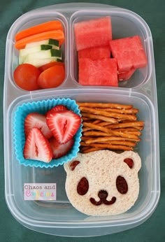 a plastic container filled with fruit and veggies on top of a green table