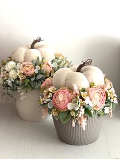 two white vases filled with flowers and pumpkins