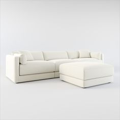 a white couch and ottoman in front of a gray wall with no one sitting on it