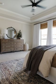 a bedroom with a bed, dresser and ceiling fan in the middle of the room