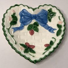 a decorative heart shaped dish with blue birds on it's sides and berries in the center