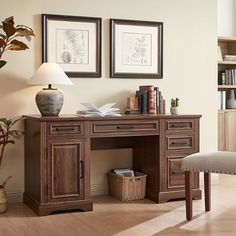 a wooden desk with two pictures on the wall above it and a chair next to it