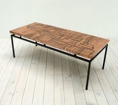 a wooden table with black metal legs on a white floor