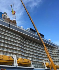 a crane is working on the side of a cruise ship