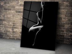 a black and white photo of a naked woman in front of a brick wall with a window