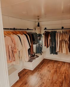 a room filled with lots of clothes hanging on the wall and wooden floors in front of it