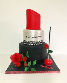 a black and white cake with red roses on the top is decorated with mac cosmetics