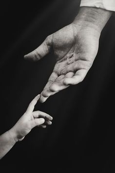 two people reaching out their hands to touch each other's hand, in black and white