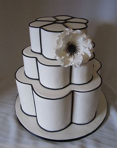 a three tiered cake with white flowers on the top and black trimmings