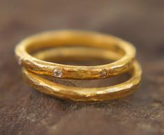 two gold rings with diamonds sitting on top of each other