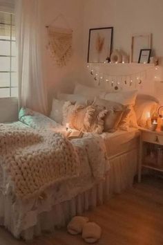 a bedroom with white bedding and lights on the windows sill above it is lit by candles