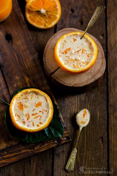 two orange halves with yogurt in them on a cutting board next to sliced oranges