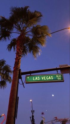 the street sign for las vegas boulevard is lit up at night with palm trees in the foreground