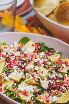 a salad with apples, cheese and pomegranates in a bowl