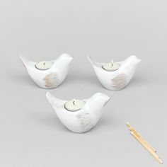 three white ceramic birds with candles and chopsticks