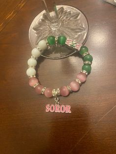 Gorgeous tricolor bracelet with "soror" charm attached to the bracelet. Pink, green and white beads. A great gift for birthdays, anniversaries, AKAversaries, etc. Avoid exposing the charms to water to prevent tarnishing. Personalized Green Bracelets As Gifts, Green Beaded Bracelets With Charms As Gift, Green Beaded Charms Bracelets As Gift, Personalized Green Name Bracelet As Gift, Personalized Green Name Bracelet For Gift, Green Charm Bracelet As A Gift, Green Bracelets With Letter Beads For Gifts, Personalized Green Beaded Bracelets With Letter Beads, Green Bracelet With Letter Beads As Gift