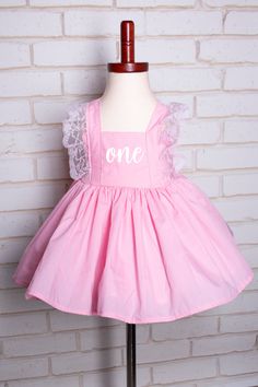 As a professional photographer I loved the poofy dresses for 1st birthday photos but hated cleaning the tulle.  This dress is made of cotton so it is easier to wash and use again, whether for everyday use or for a special cake smash session. This handmade dress is pink with pink lace trim and perfect for that fairy or princess on the go!  It is made with cotton allowing her  the ability to have fun as well as washable for the grown ups. Included are a pair of pink romper shorts as well as a detached cotton white petticoat skirt to add volume.   Dress is fully lined. If choosing a different color the bloomers will be the same color as the dress. This dress can be made in sizes 12 months to 14 years. For customization simply choose from the font/words you want from the gallery.  In the custo Spring Princess Dress With Ruffles For First Birthday, Princess Style Dress With Ruffles For First Birthday, Summer Princess Dress With Ruffles For First Birthday, Cute Princess Dress With Ruffles For Birthday, Cute Ruffled Princess Dress For Birthday, First Birthday Princess Dress With Ruffles, Princess Ruffle Dress For First Birthday, Princess Dress With Ruffles For First Birthday, Princess Style Ruffled Dress For First Birthday