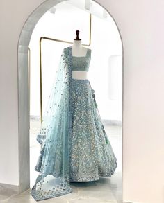 a blue lehenga is on display in front of an arched doorway with a mannequin