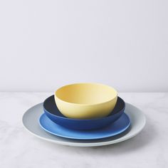 three plates stacked on top of each other with blue and yellow bowls in the middle